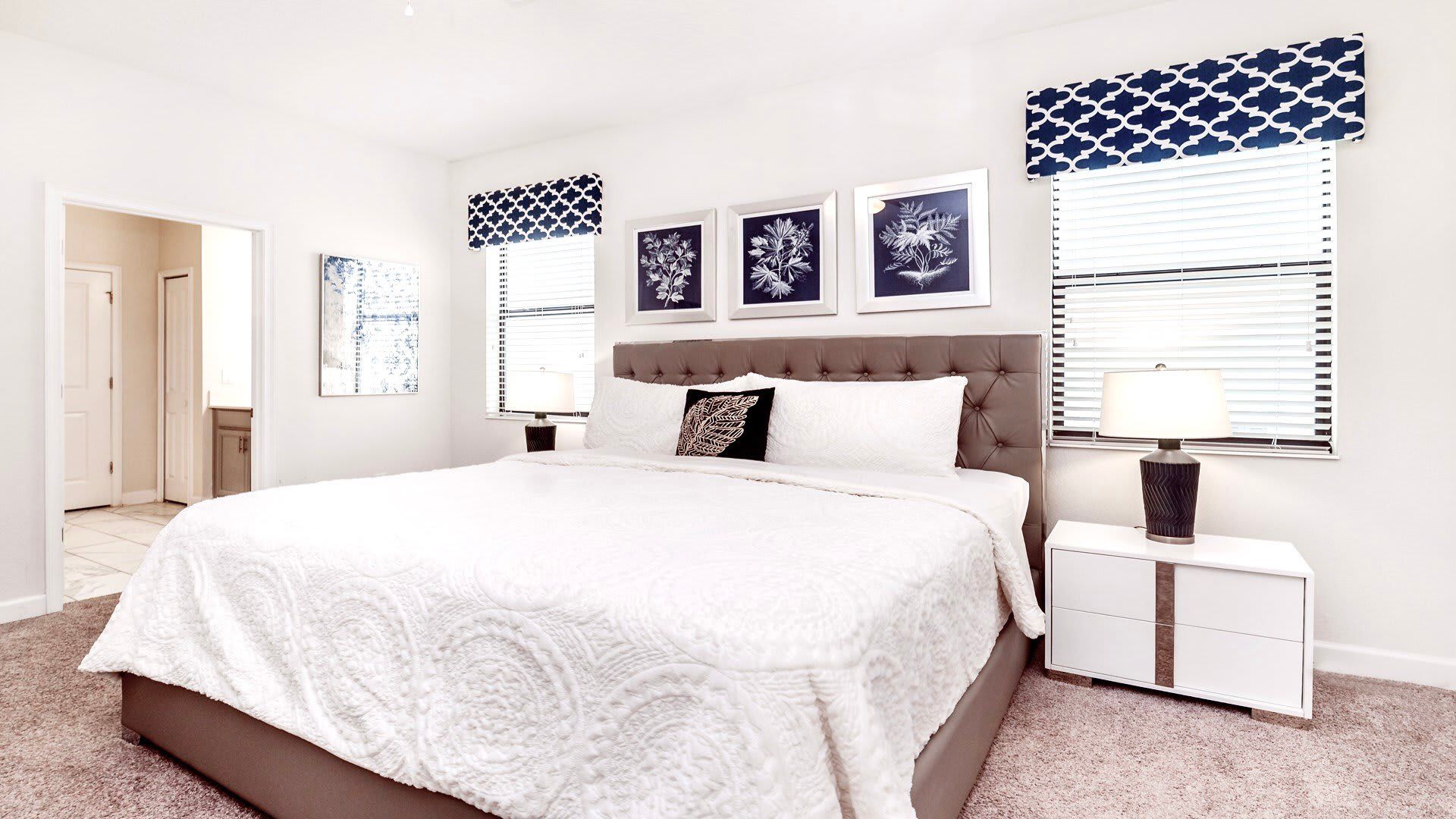 Elegant bedroom with king bed, navy accents, modern art, and cozy neutral tones