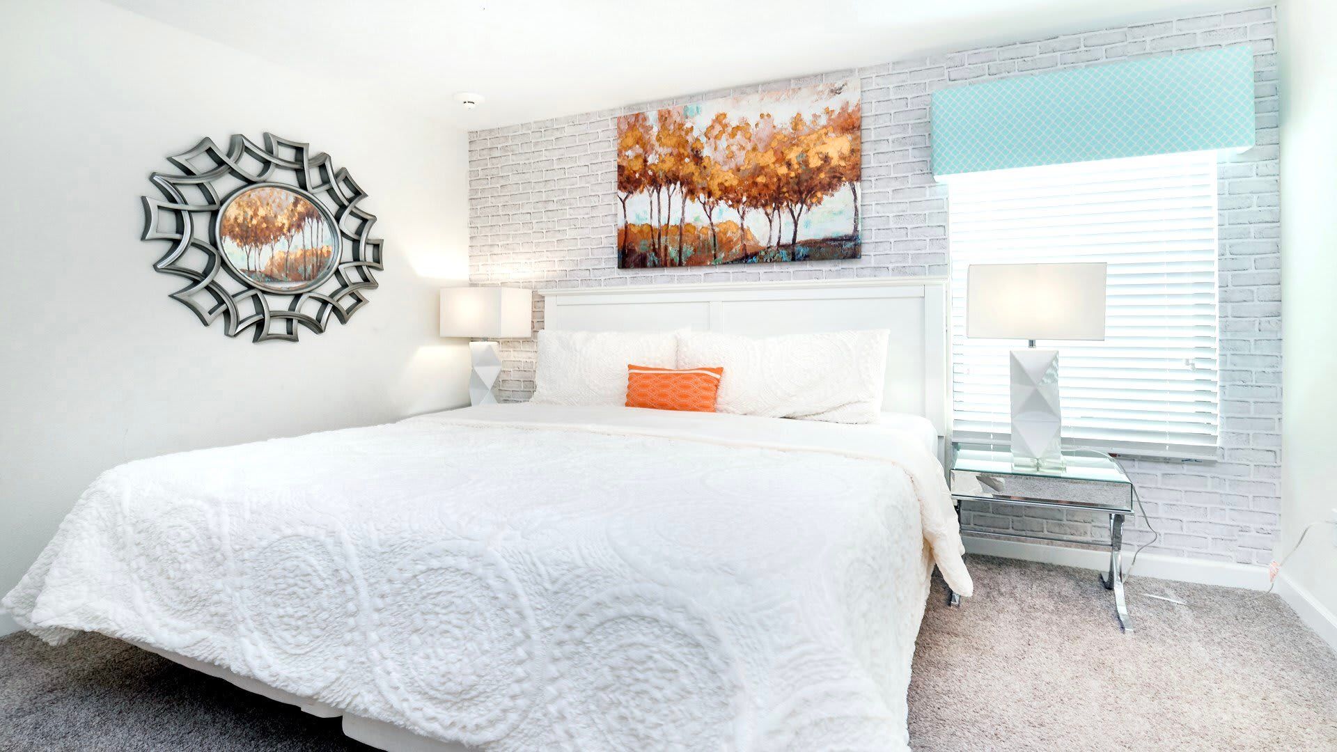 Bright and cozy bedroom with white brick accents, king bed, and autumn artwork