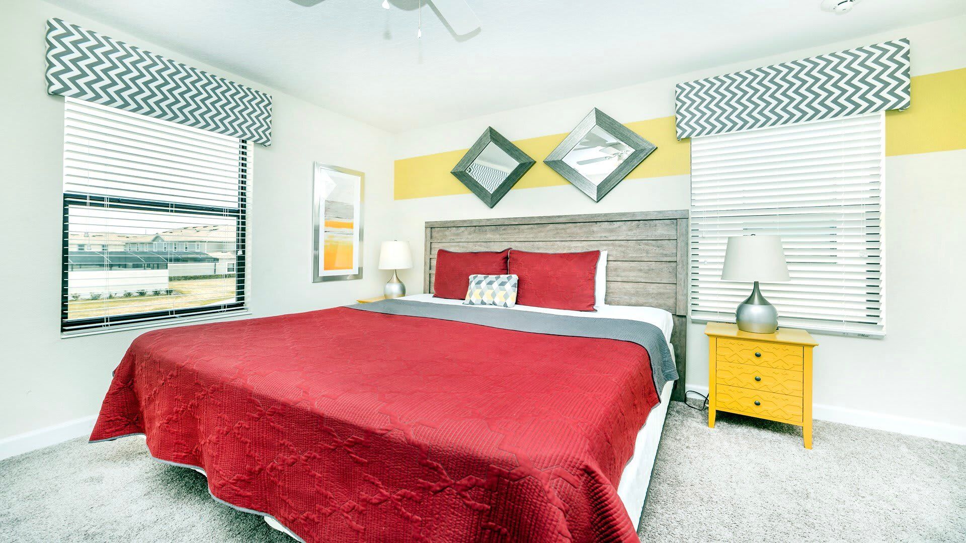 Vibrant bedroom with bold red bedding, modern accents, and natural light galore