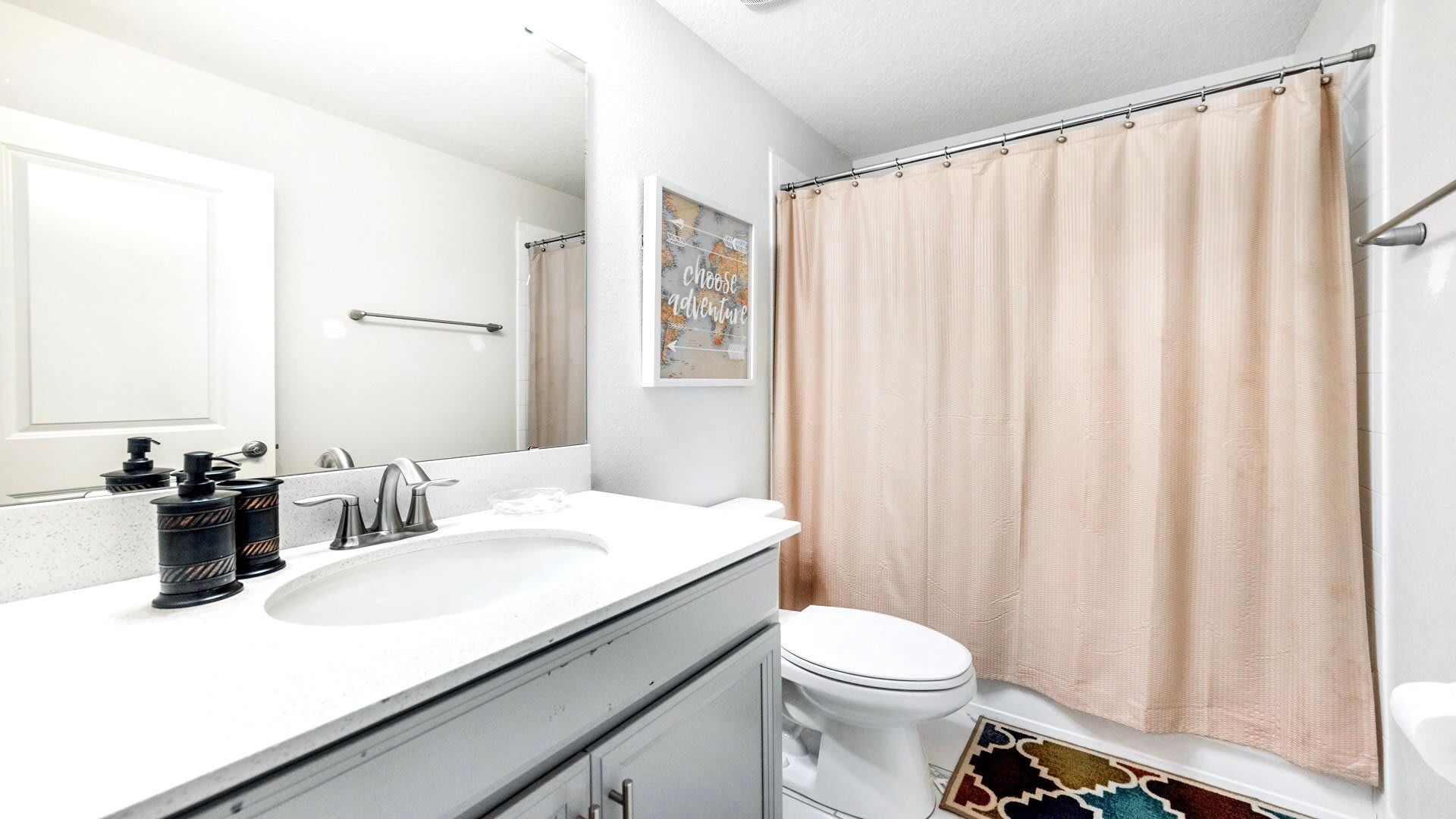 Chic guest bathroom with quartz vanity, framed art, and cozy neutral shower curtain