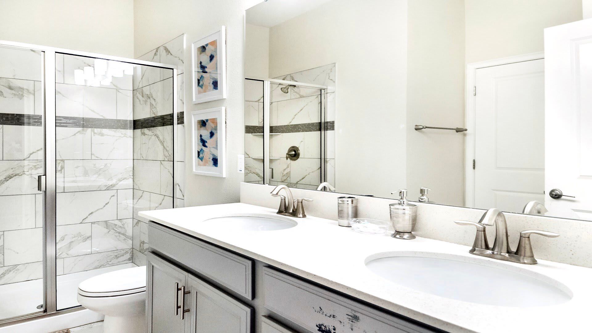 Modern bathroom with dual sinks, quartz countertops, and a sleek glass walk-in shower
