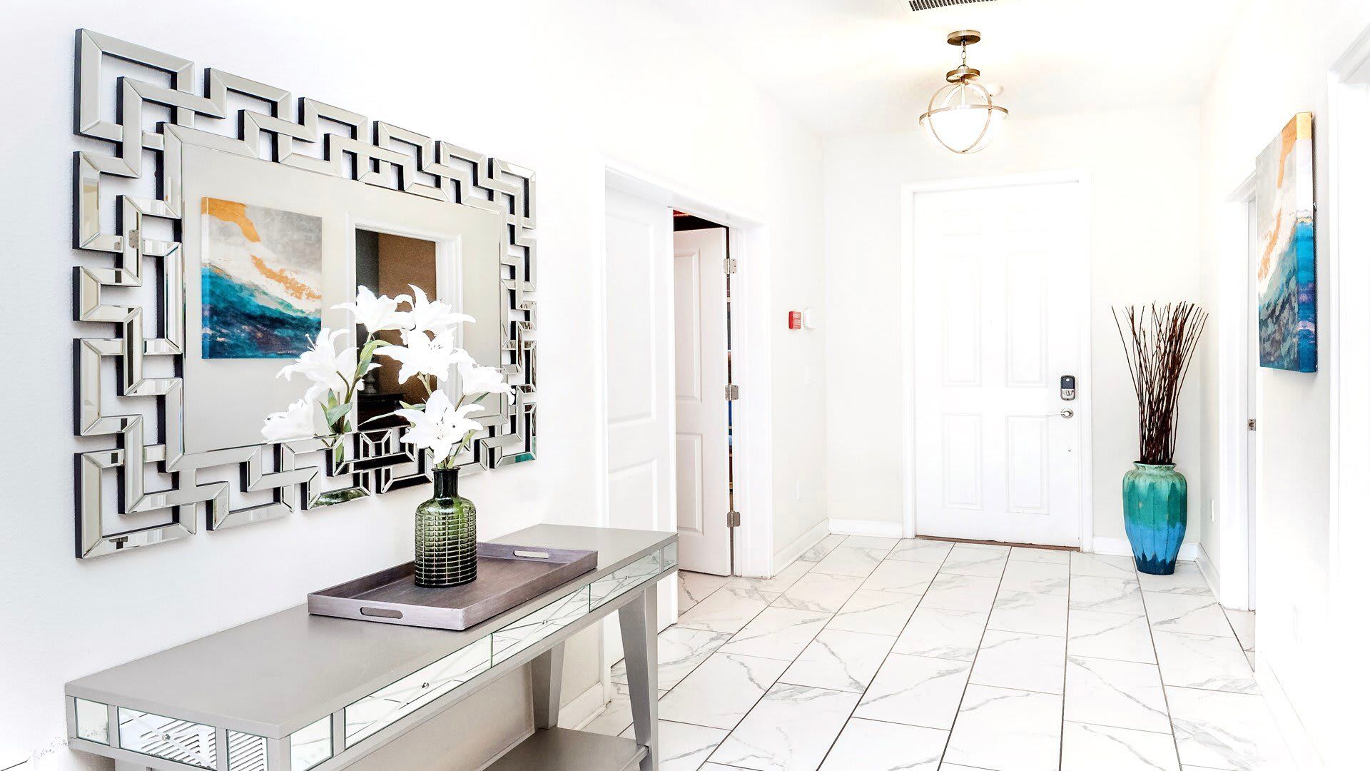 Elegant entryway with modern mirror, designer decor, and marble-style tile flooring