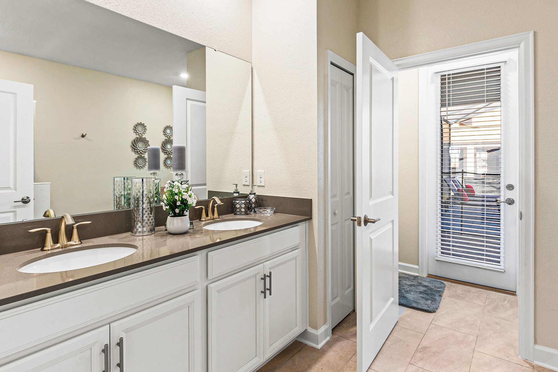 Elegant bathroom with double vanity, poolside access, and sophisticated bronze finishes