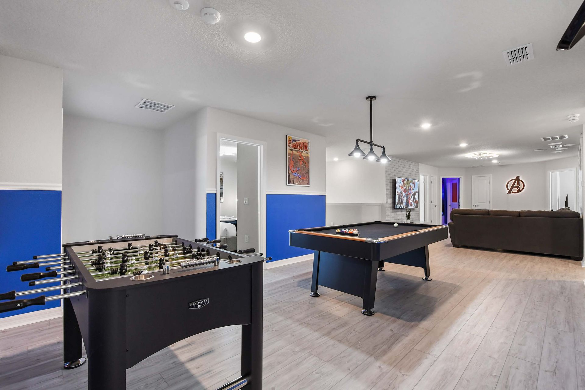 Spacious game loft with pool, foosball, lounge seating, and superhero touches