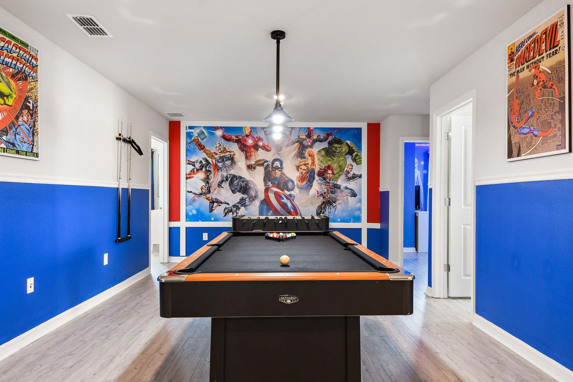 Superhero-themed game room with bold wall art and a sleek black pool table