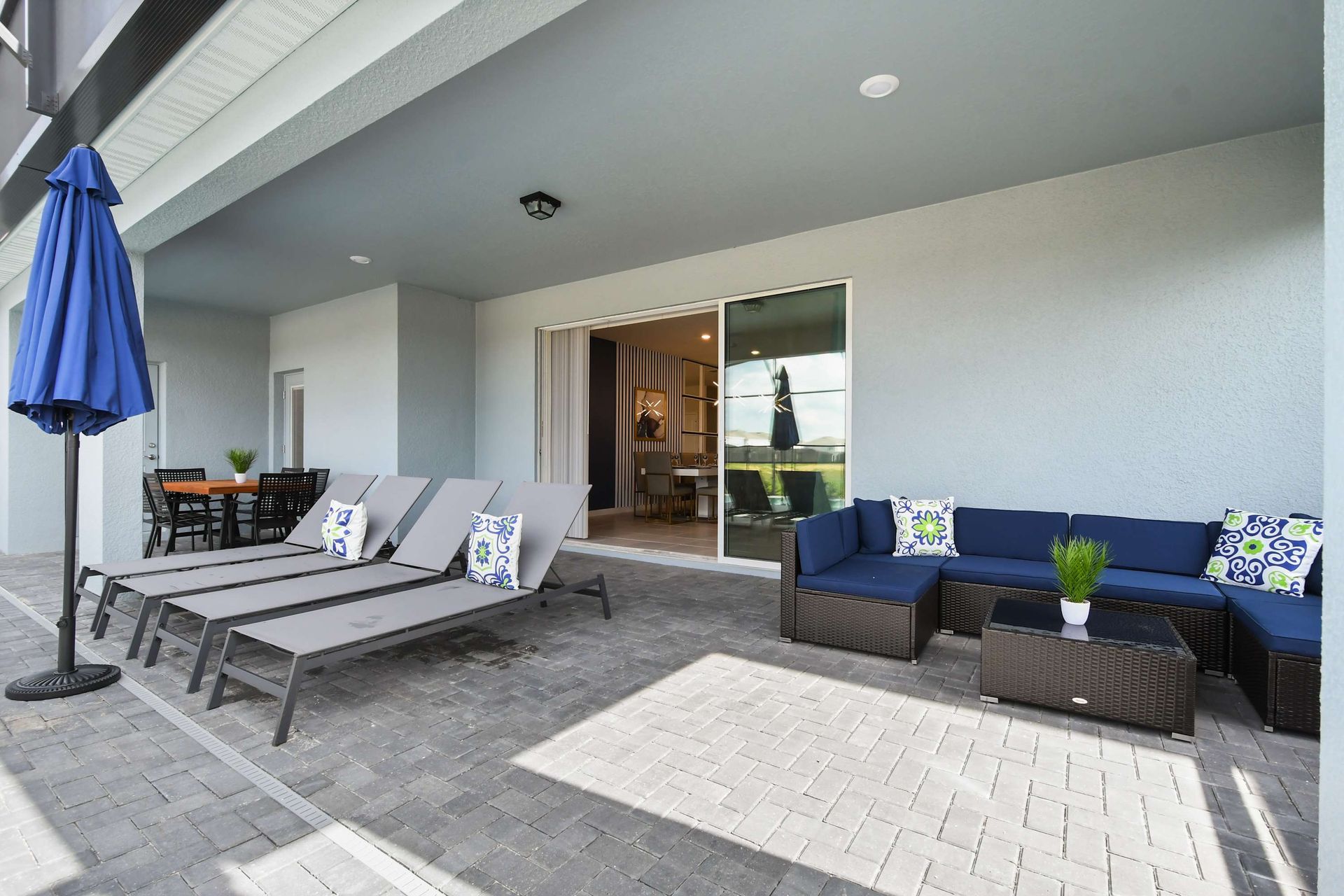 Spacious lanai with lounge chairs, outdoor sofa seating, and dining area by the pool