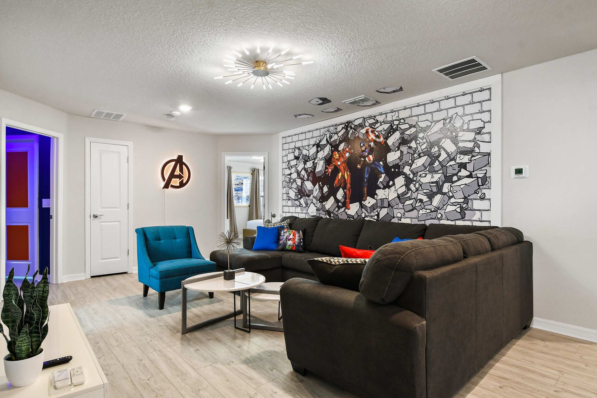 Hero-themed lounge with bold mural, cozy sectional, and vibrant accent décor