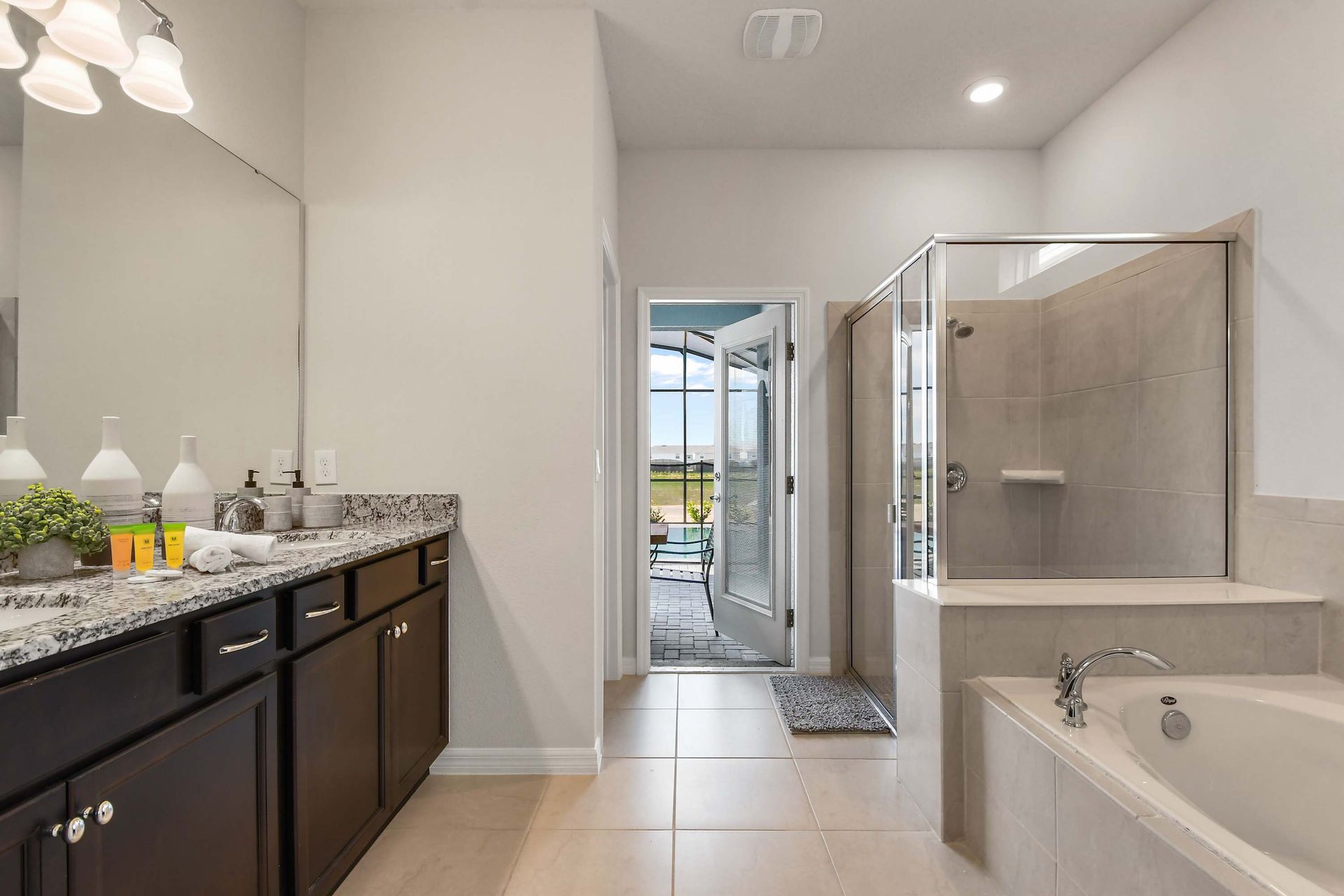 Luxurious bathroom with dual sinks, walk-in shower, soaking tub, and poolside access