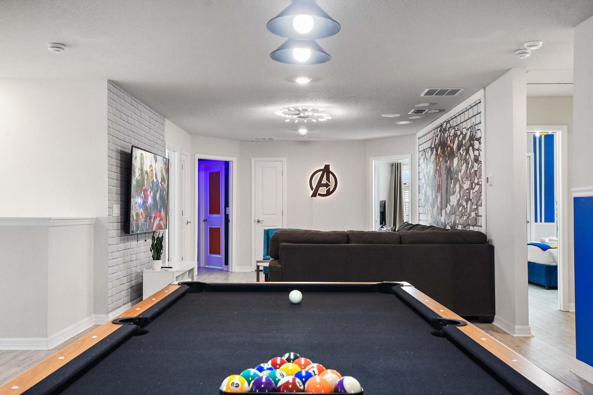 Spacious game loft with pool, foosball, lounge seating, and superhero touches