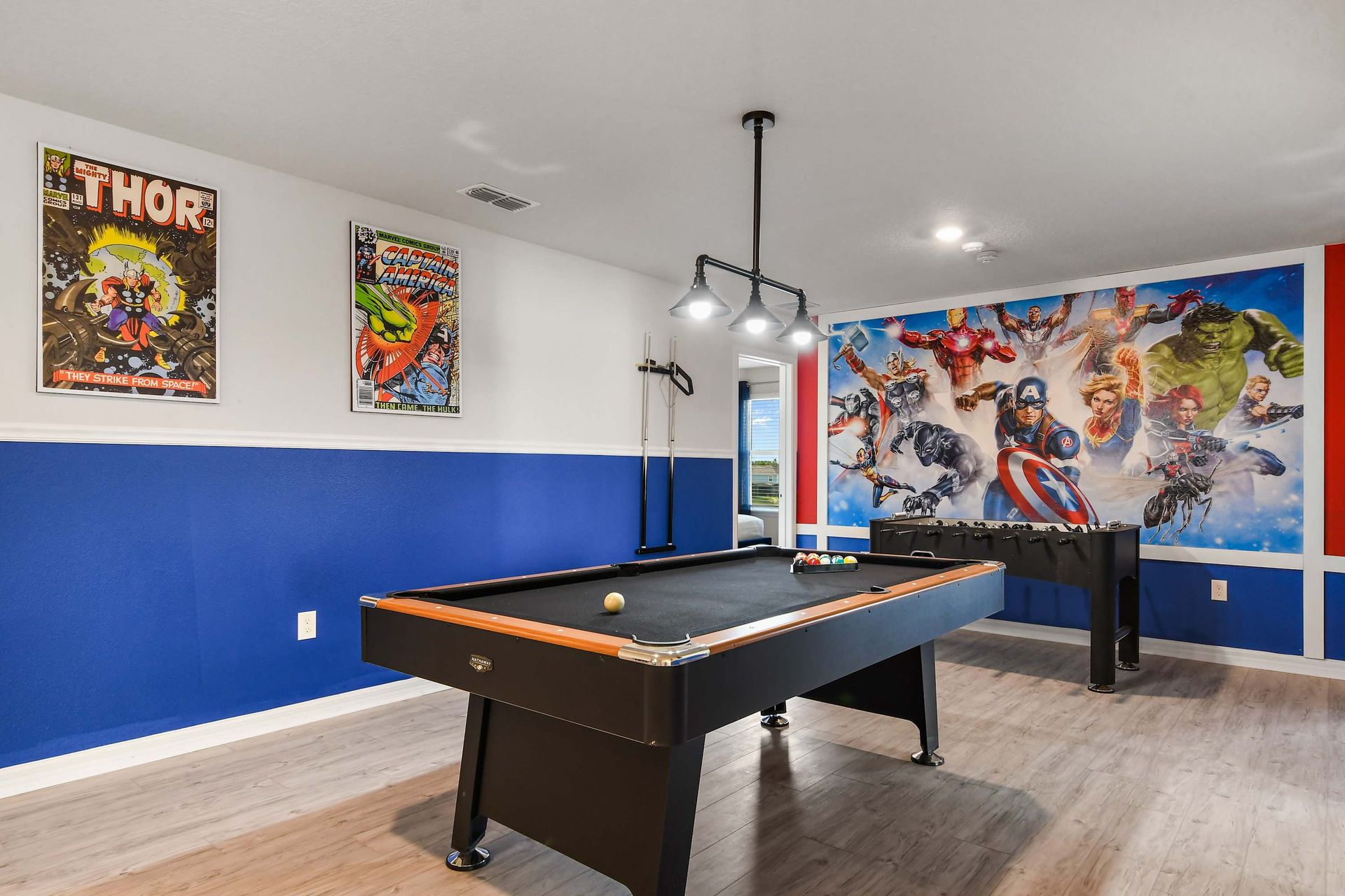 Spacious game loft with pool, foosball, lounge seating, and superhero touches