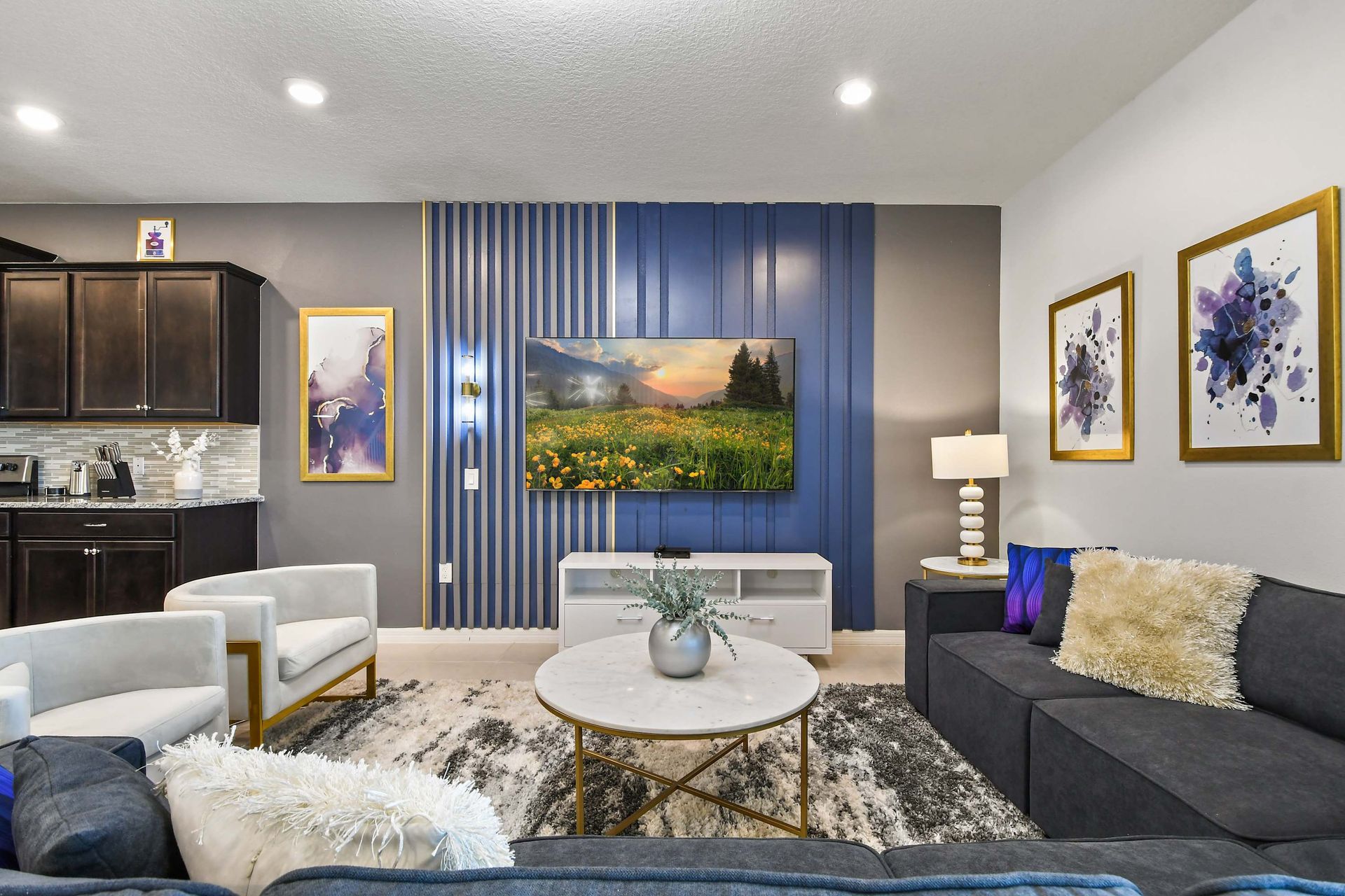 Stylish living room with sleek TV wall, cozy seating, and modern gold accents