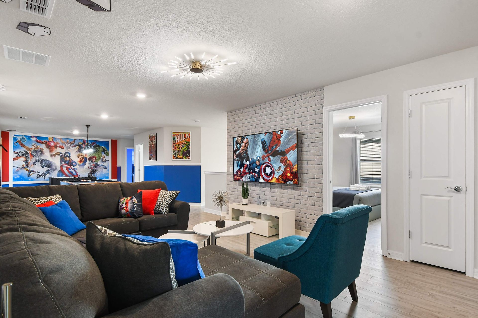 Hero-themed lounge with bold mural, cozy sectional, and vibrant accent décor
