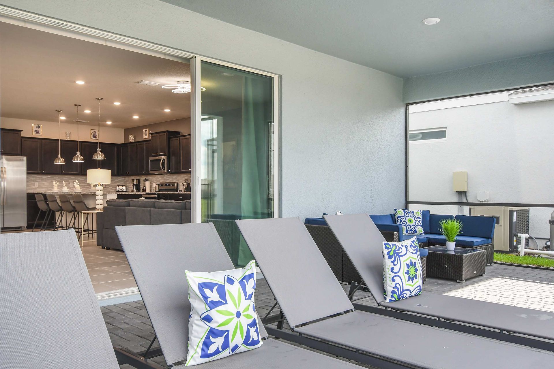 Relaxing screened-in pool and spa with sun loungers, dining table, and open views