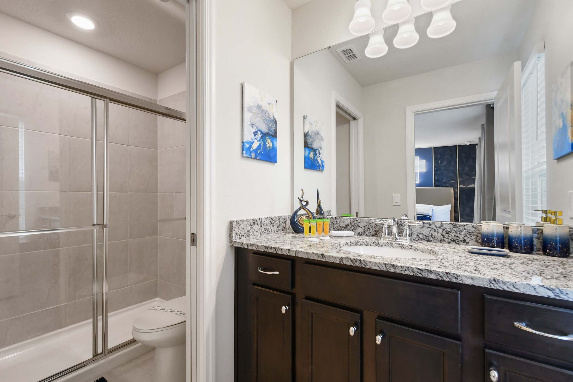 Bright and stylish bathroom featuring a granite countertop, dark wood cabinetry, and a sleek glass-enclosed shower. 