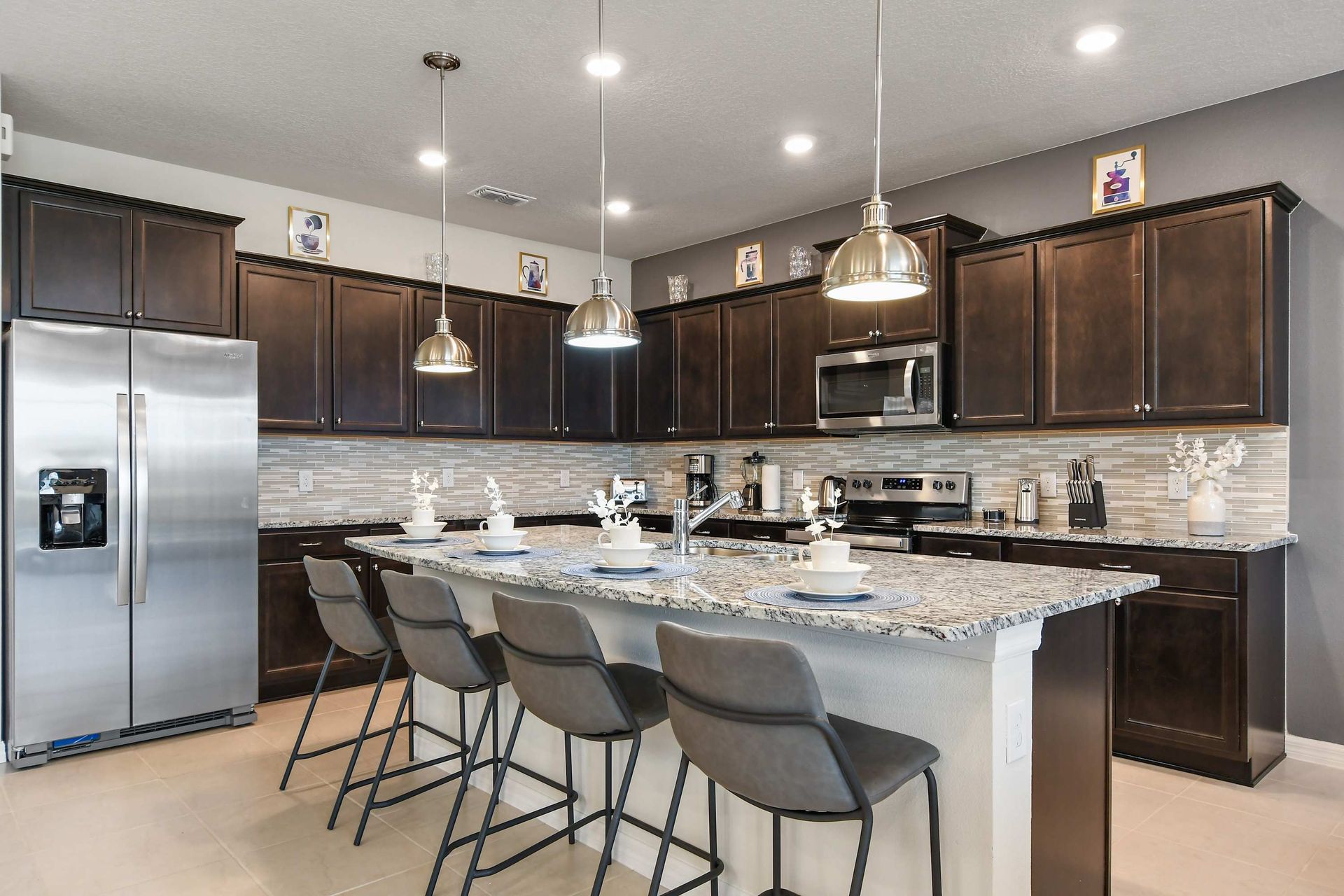 Modern open kitchen with granite island, pendant lights, and seating for five