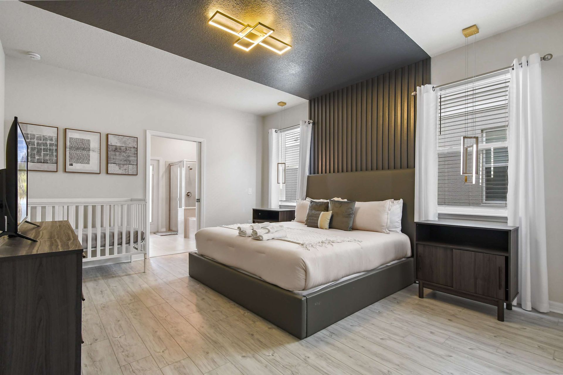 Modern master suite with king bed, stylish lighting, ensuite bath, and crib included