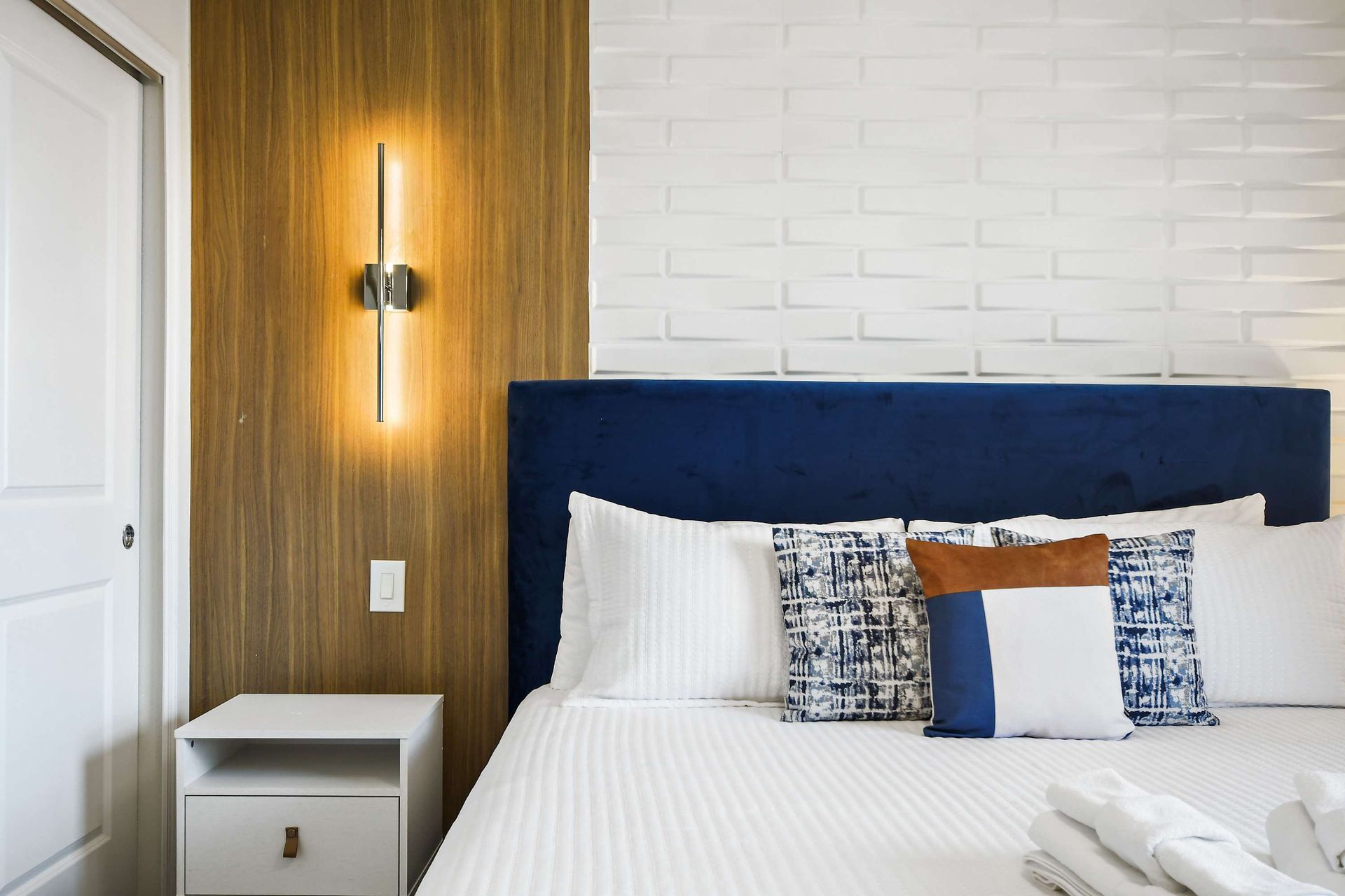 Modern king bedroom with textured accent wall, bold decor, and natural light views