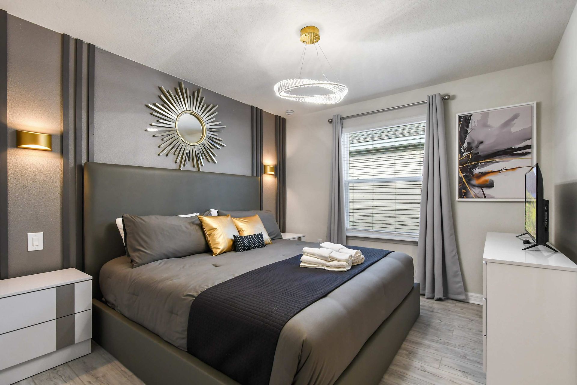 Chic bedroom with king bed, gold accents, modern lighting, and luxe gray tones