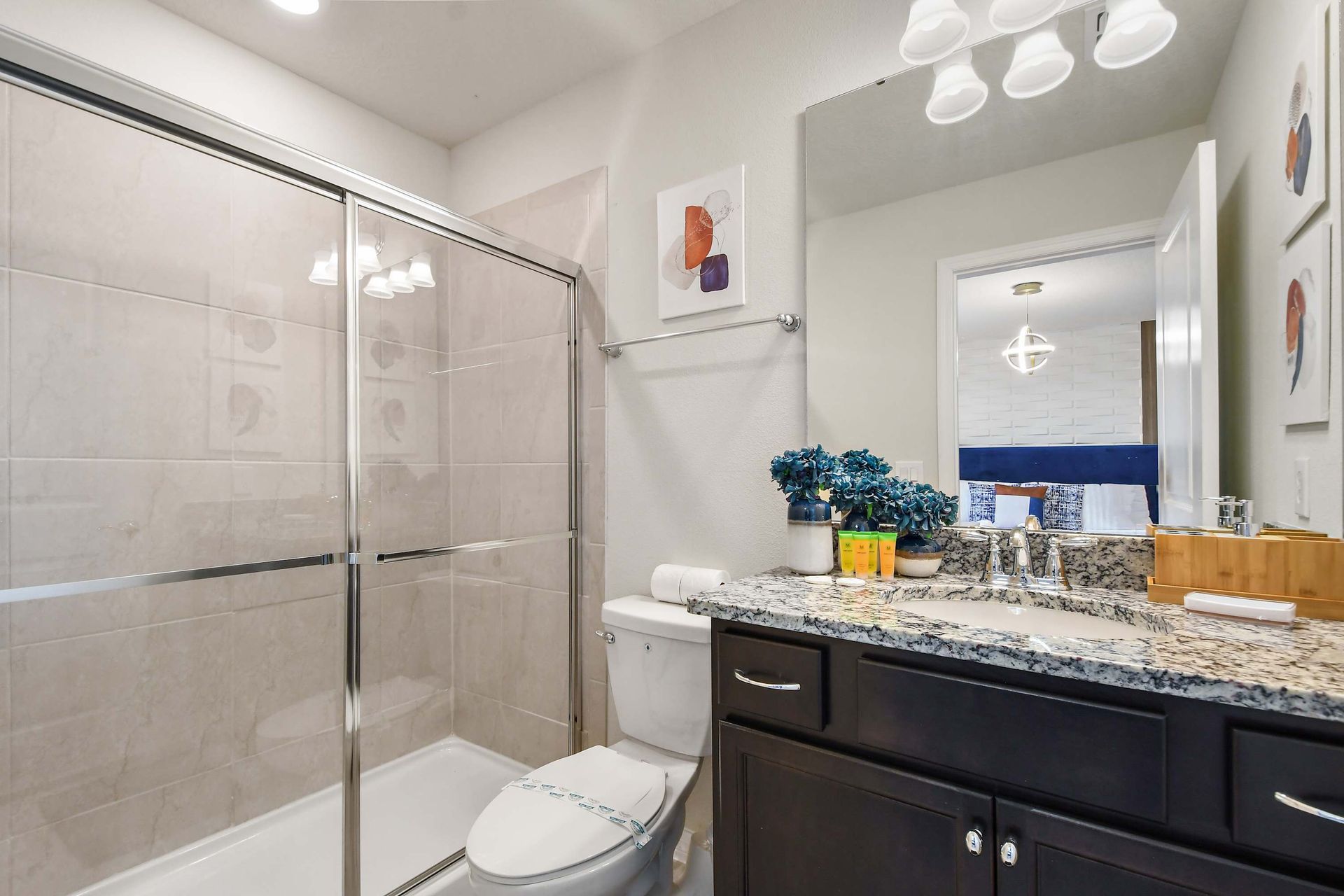 Bright and stylish bathroom featuring a granite countertop, dark wood cabinetry, and a sleek glass-enclosed shower. 