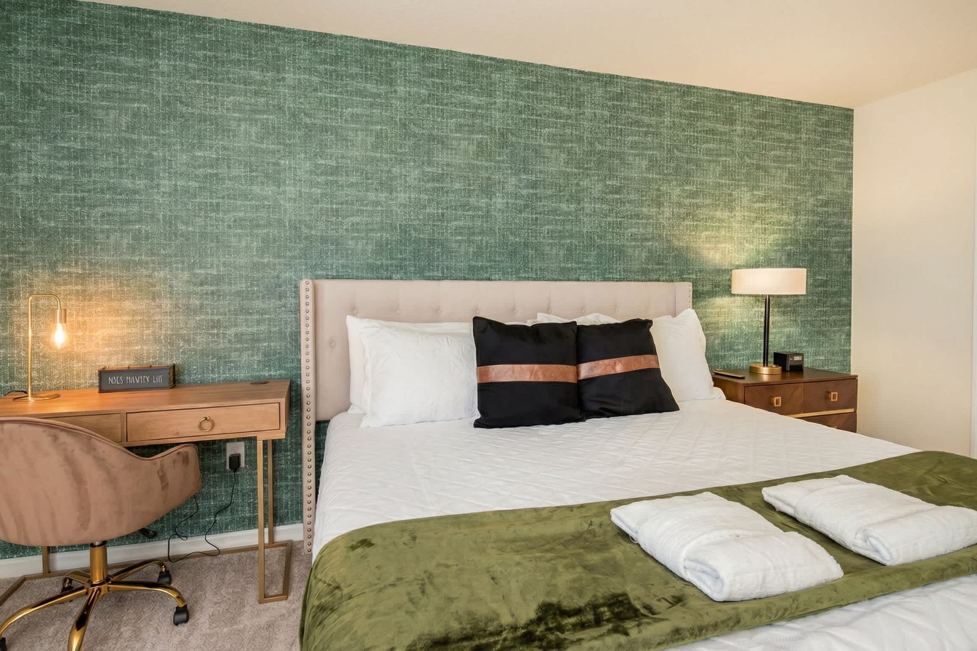 Chic bedroom with workspace, luxe bedding, and bold designer accent wall.