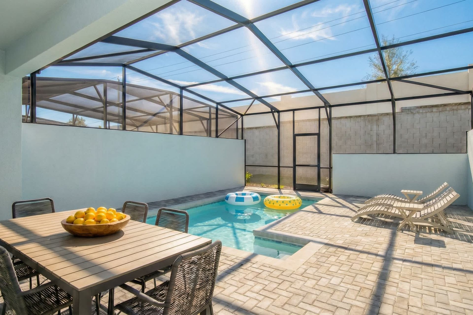 Private screened-in pool with lounge chairs, dining area, and ceiling fan comfort.