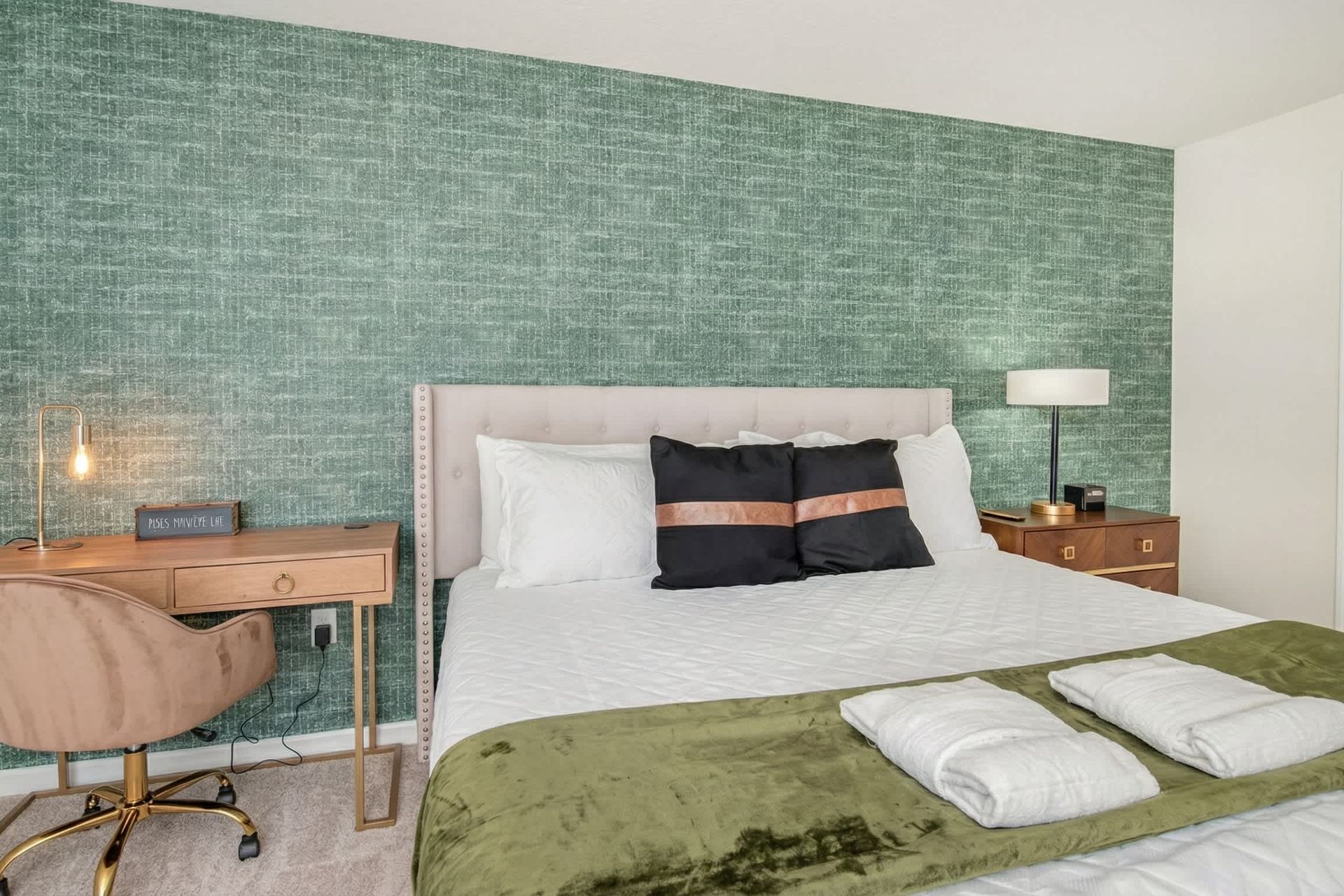 Chic bedroom with workspace, luxe bedding, and bold designer accent wall.