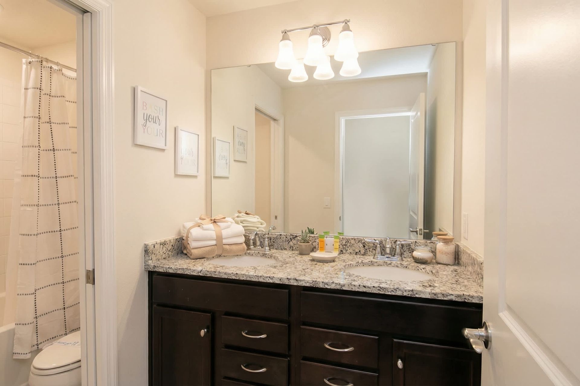 Bright bathroom with granite double vanity, full tub, and cheerful decor touches.
