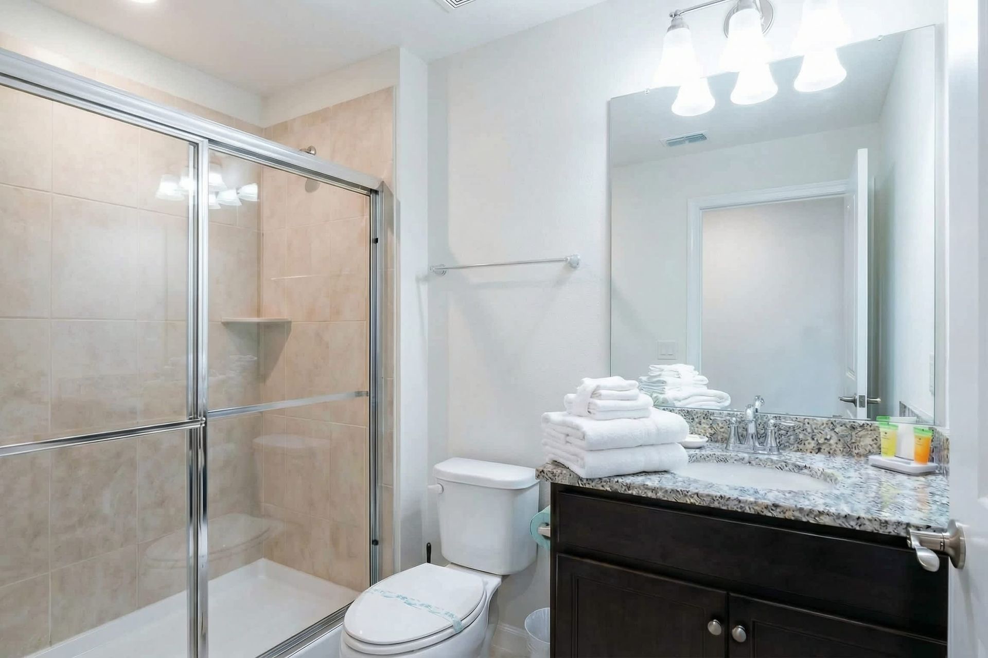 Bright bathroom with granite double vanity, full tub, and cheerful decor touches.