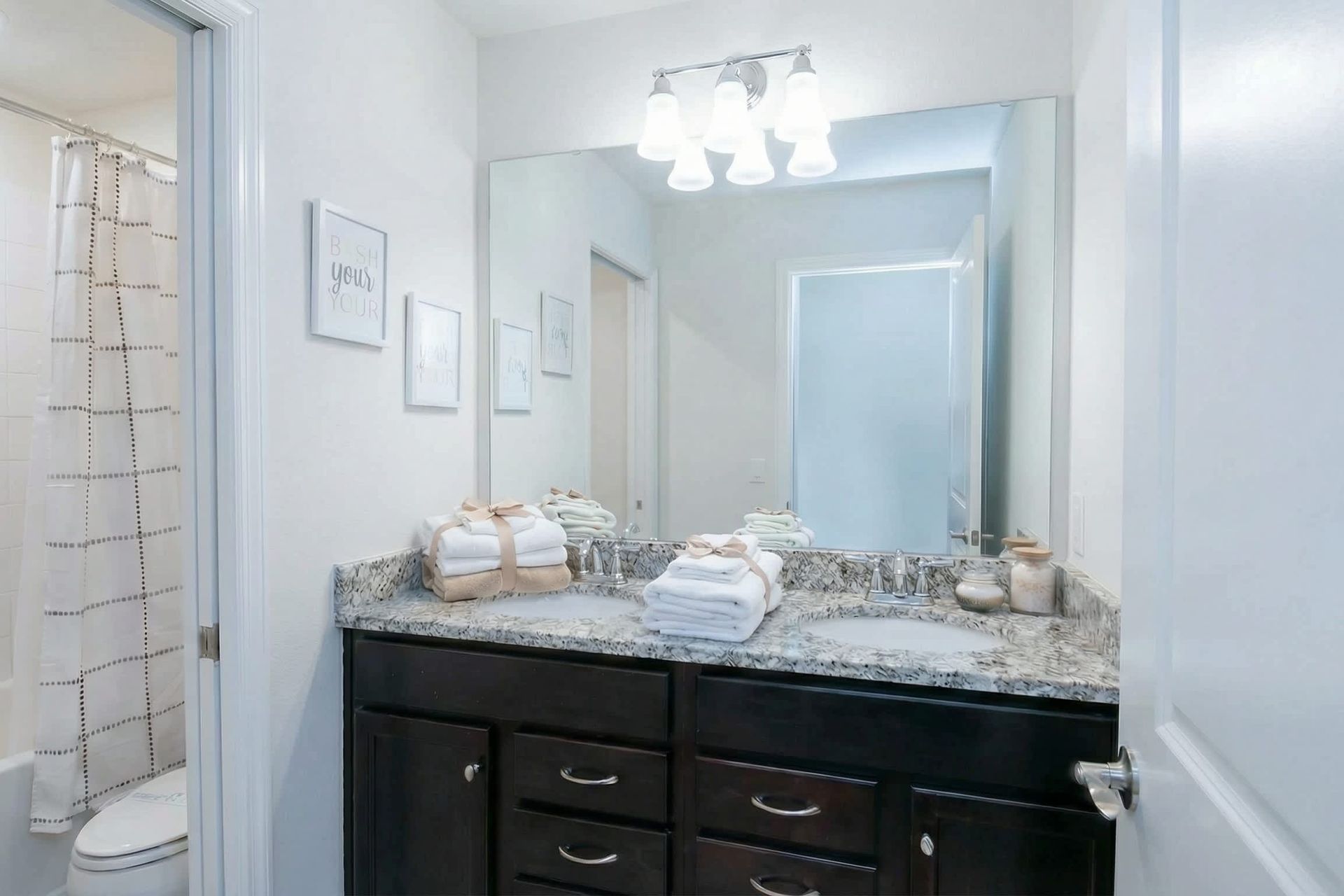 Bright bathroom with granite double vanity, full tub, and cheerful decor touches.