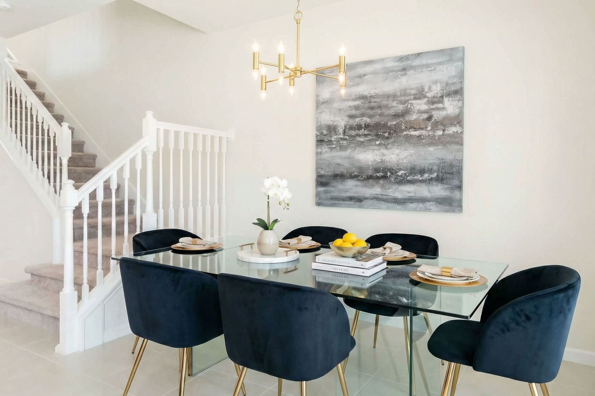 Elegant dining area with glass table, velvet chairs, and modern chandelier.