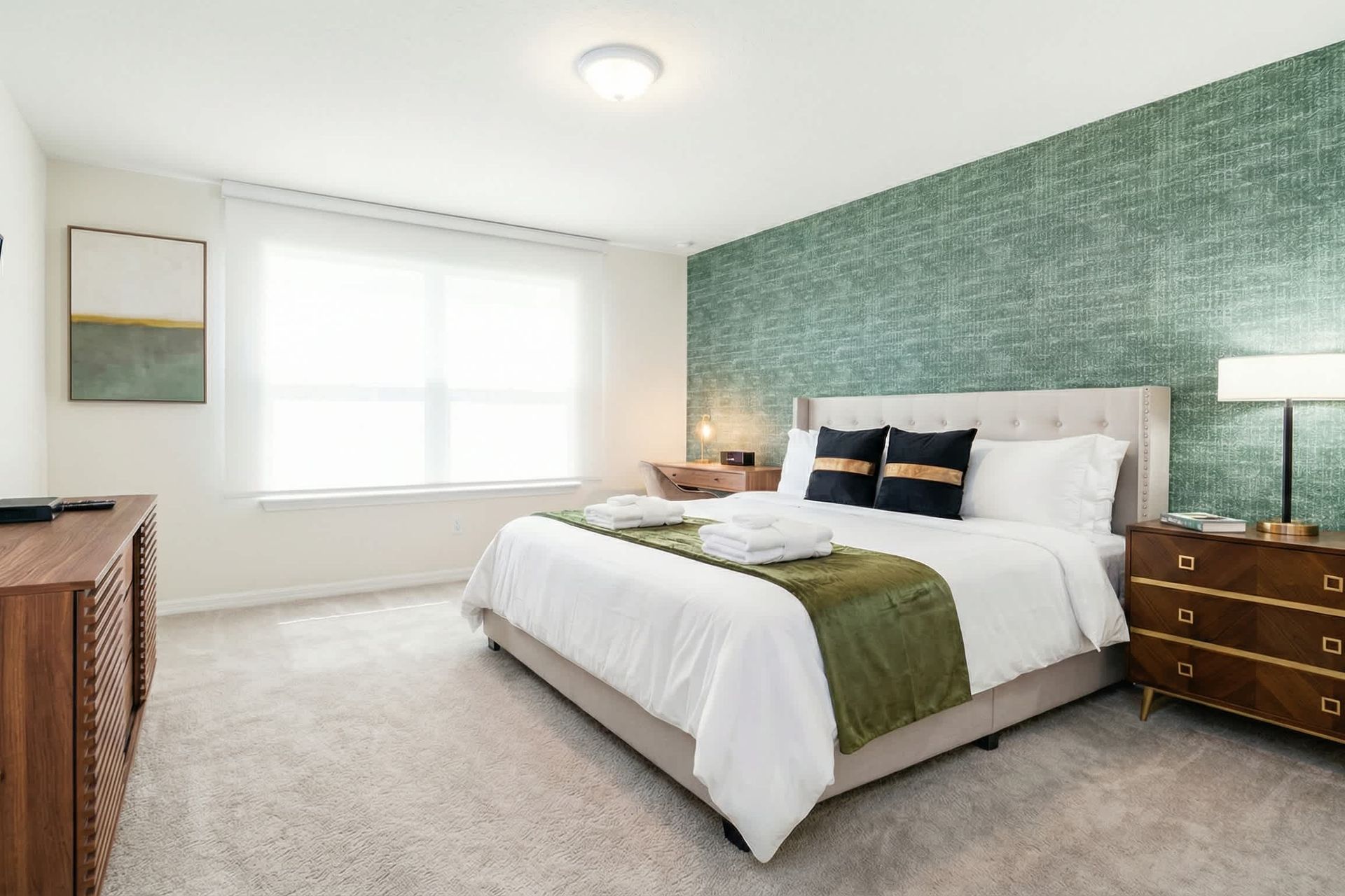 Spacious primary suite with king bed, bold accent wall, and modern furnishings.