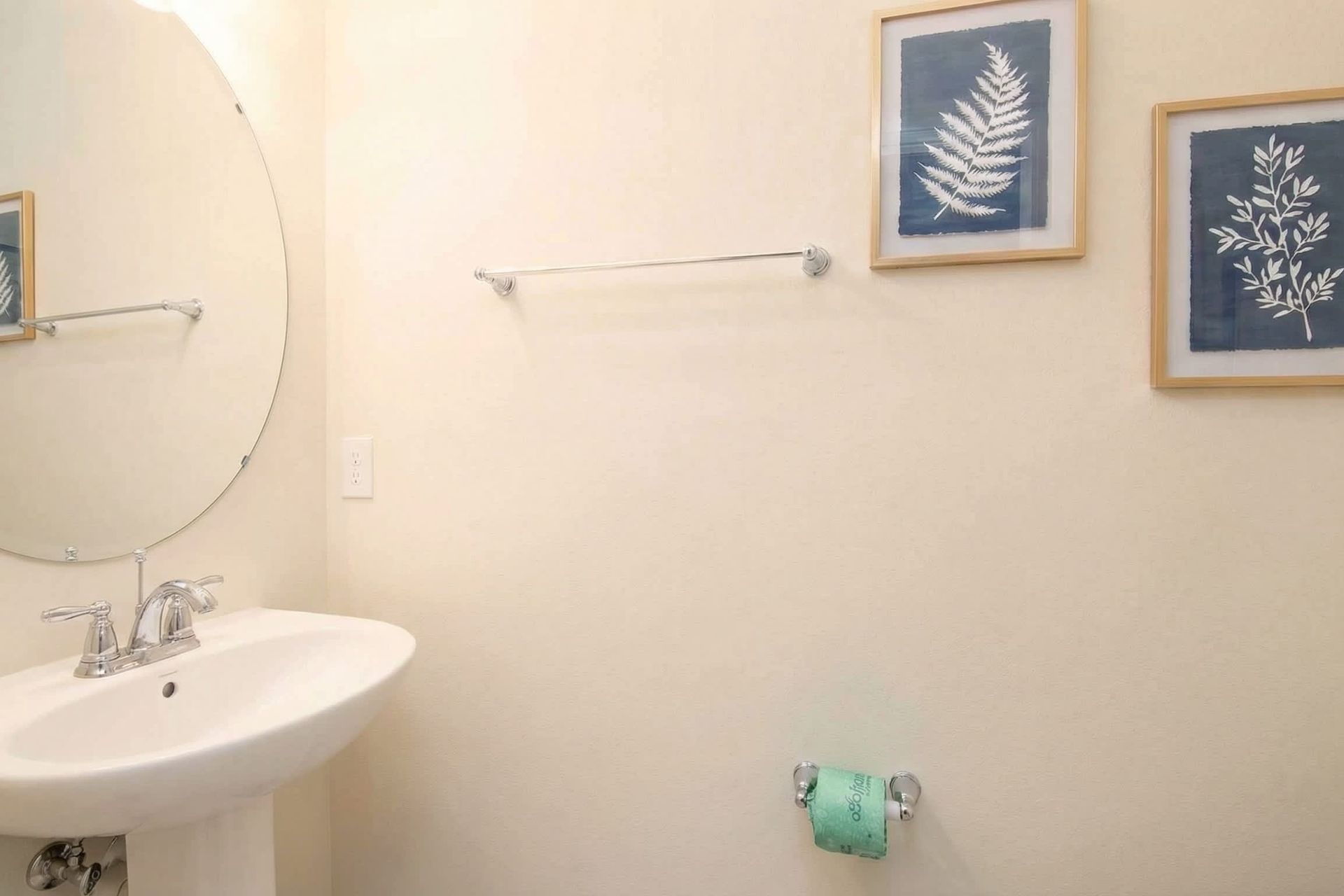 Charming half bath with pedestal sink, botanical art, and bright modern style.