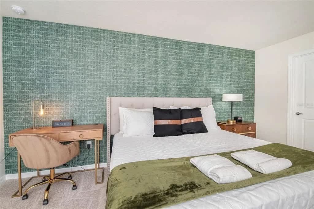 Chic bedroom with workspace, luxe bedding, and bold designer accent wall.