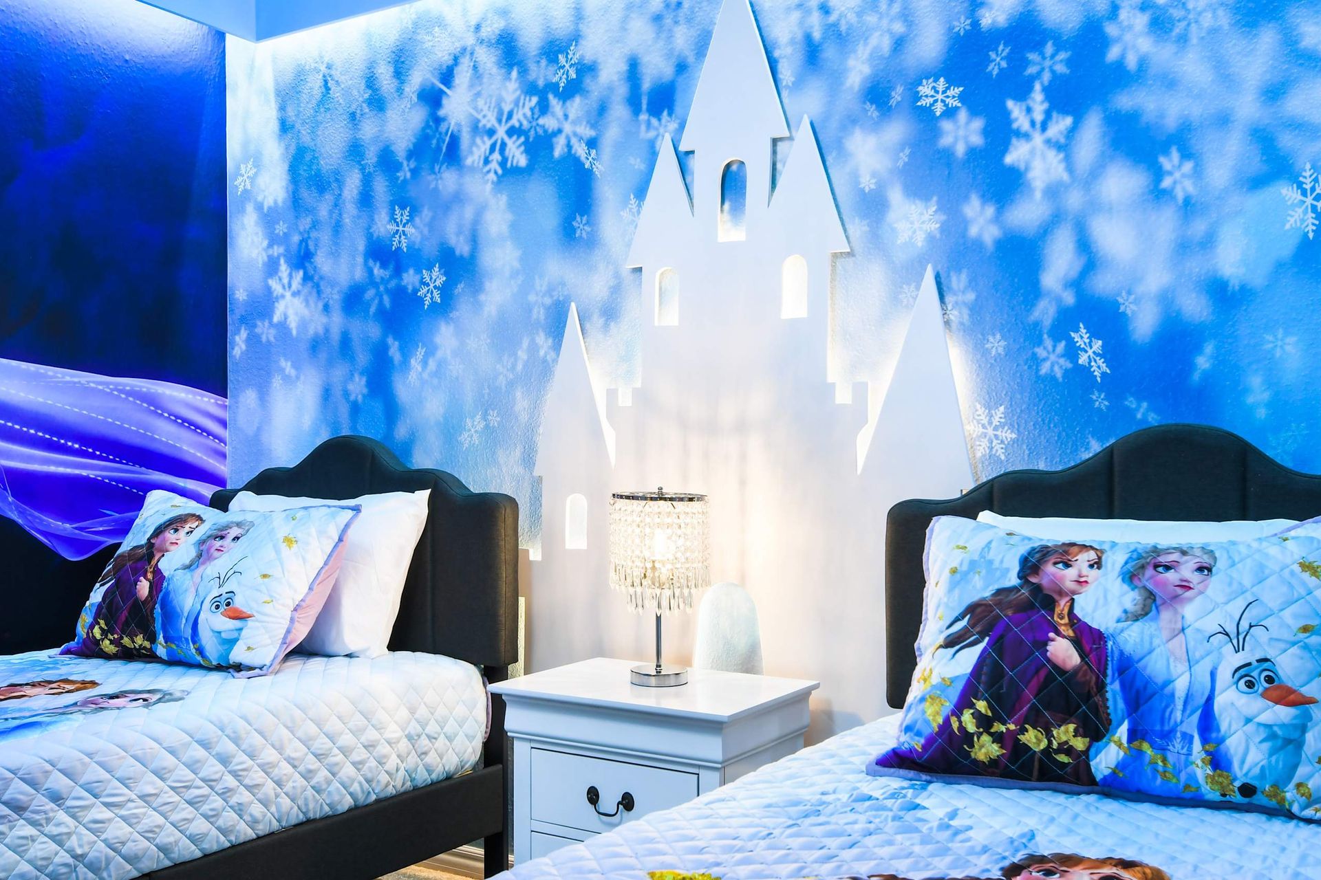 Enchanting Frozen kids’ room with snowflake walls, castle mural, and cozy twin beds
