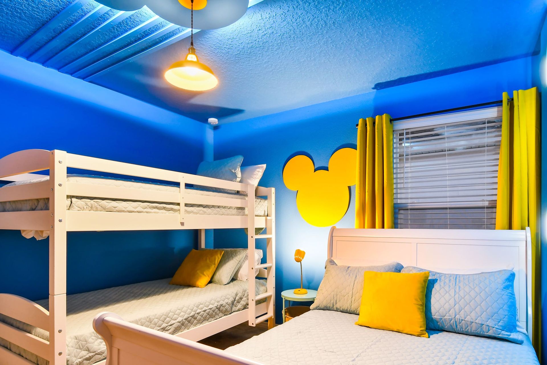 Cheerful Mickey-themed bunk room with bright blue walls, yellow accents, and fun beds
