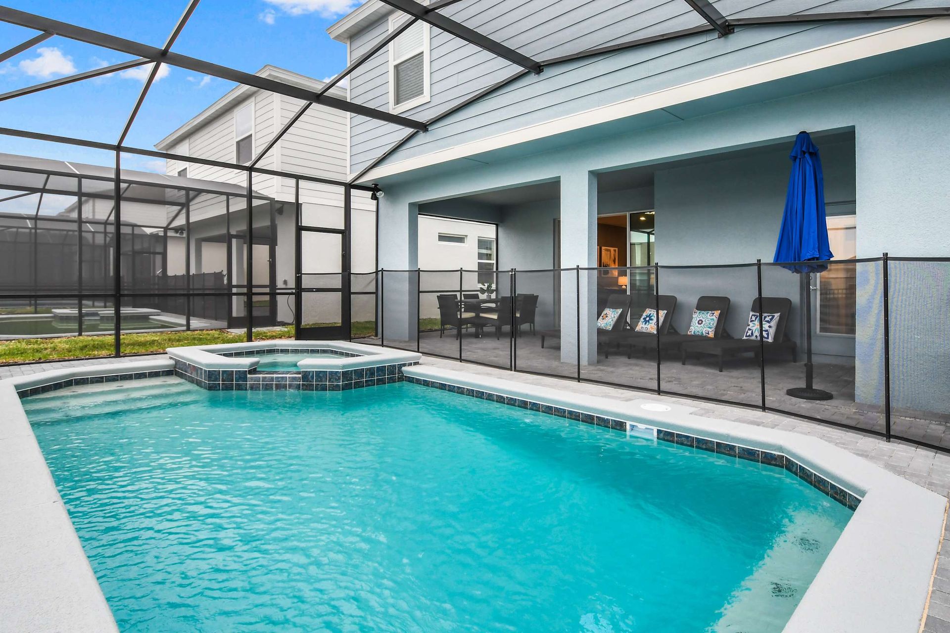 Sunny screened pool and spa with patio seating, perfect for relaxing family fun
