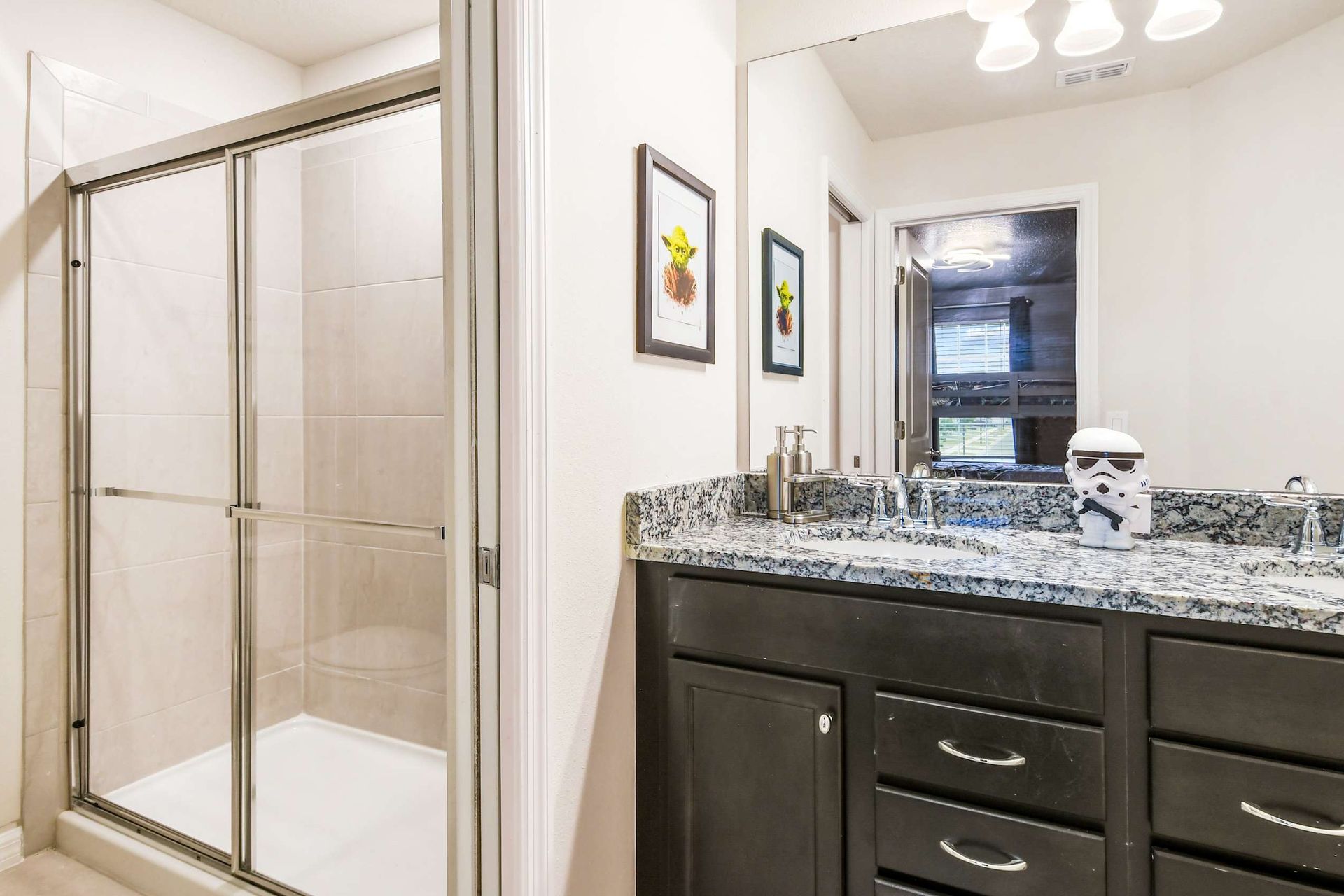 Modern bathroom with granite counter, glass shower, and playful Star Wars accent
