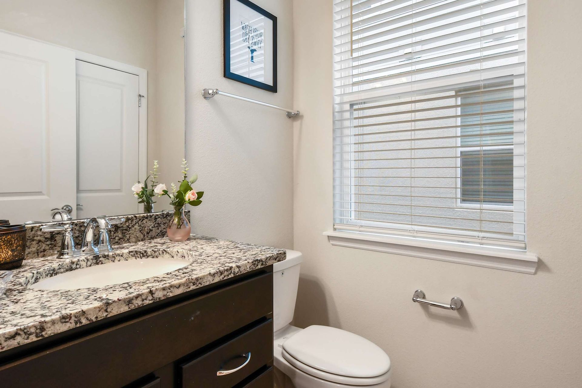 Bright modern bathroom with granite vanity, large mirror, and plenty of natural light
