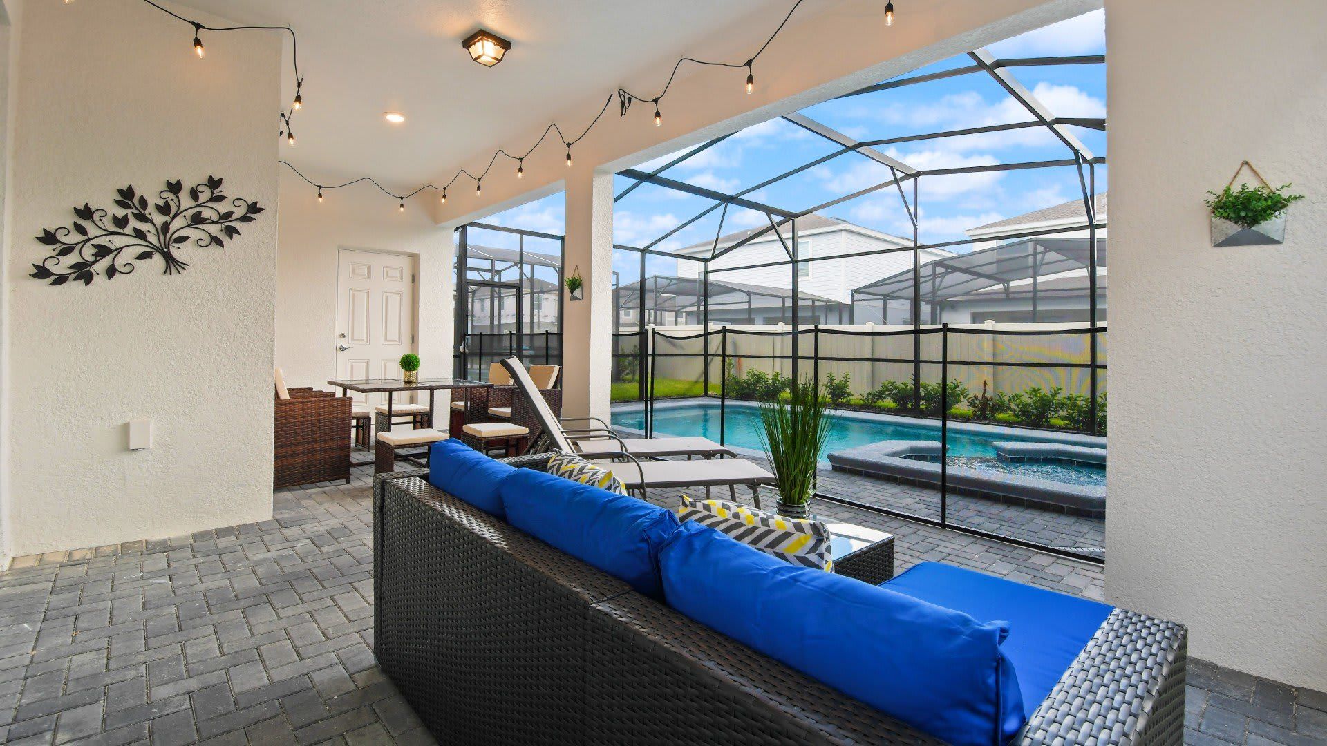 Relaxing lanai with string lights, comfy seating, and screened-in pool and spa access.