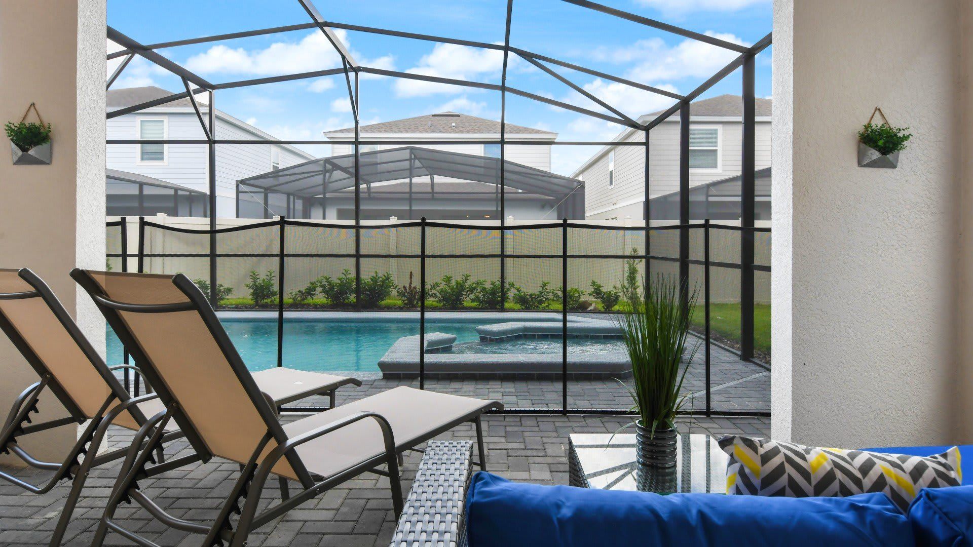 Peaceful poolside patio with lounge chairs, spa views, and screened enclosure.