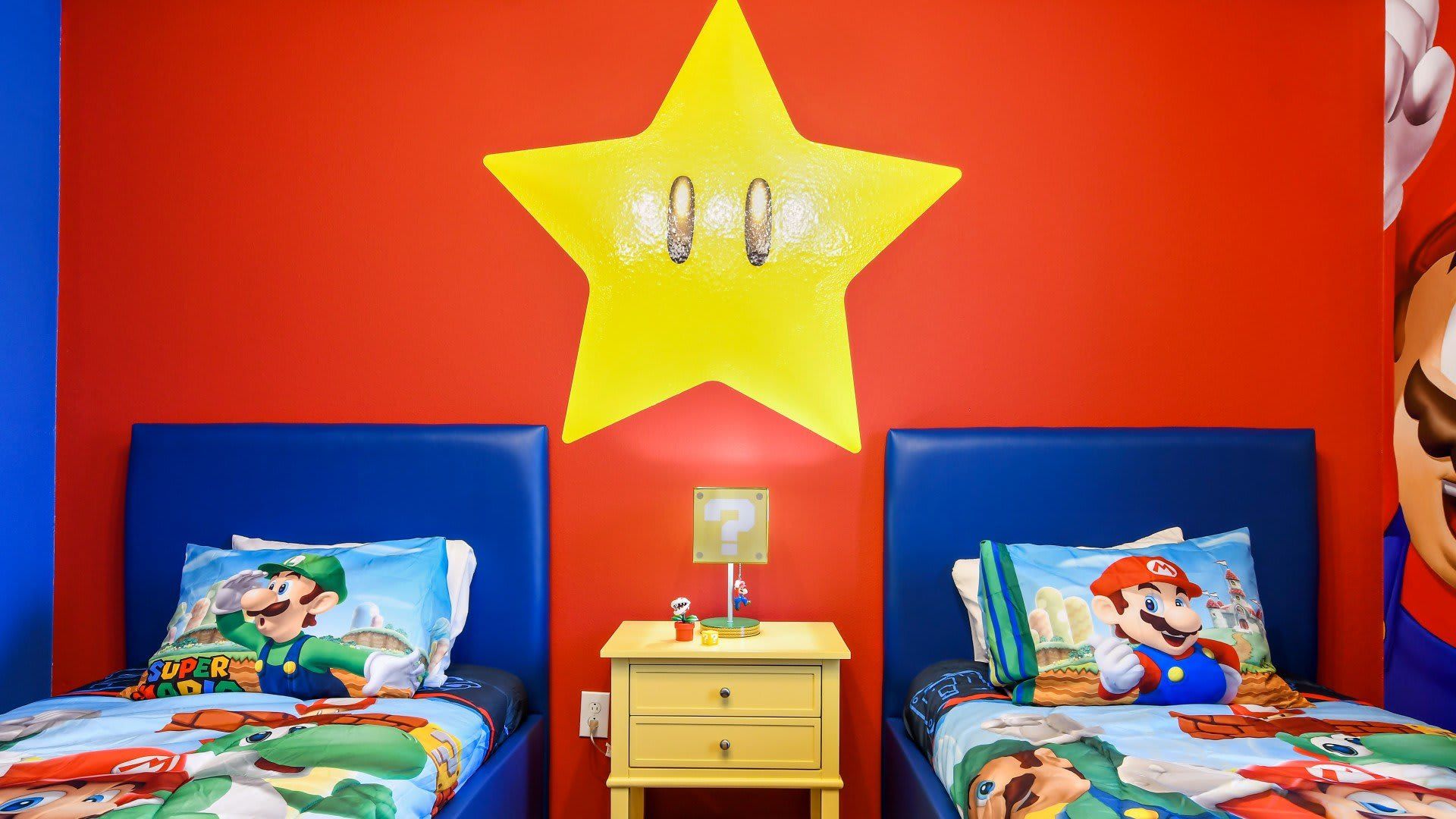Super Mario-themed twin room with bold colors, star wall light, and playful decor.