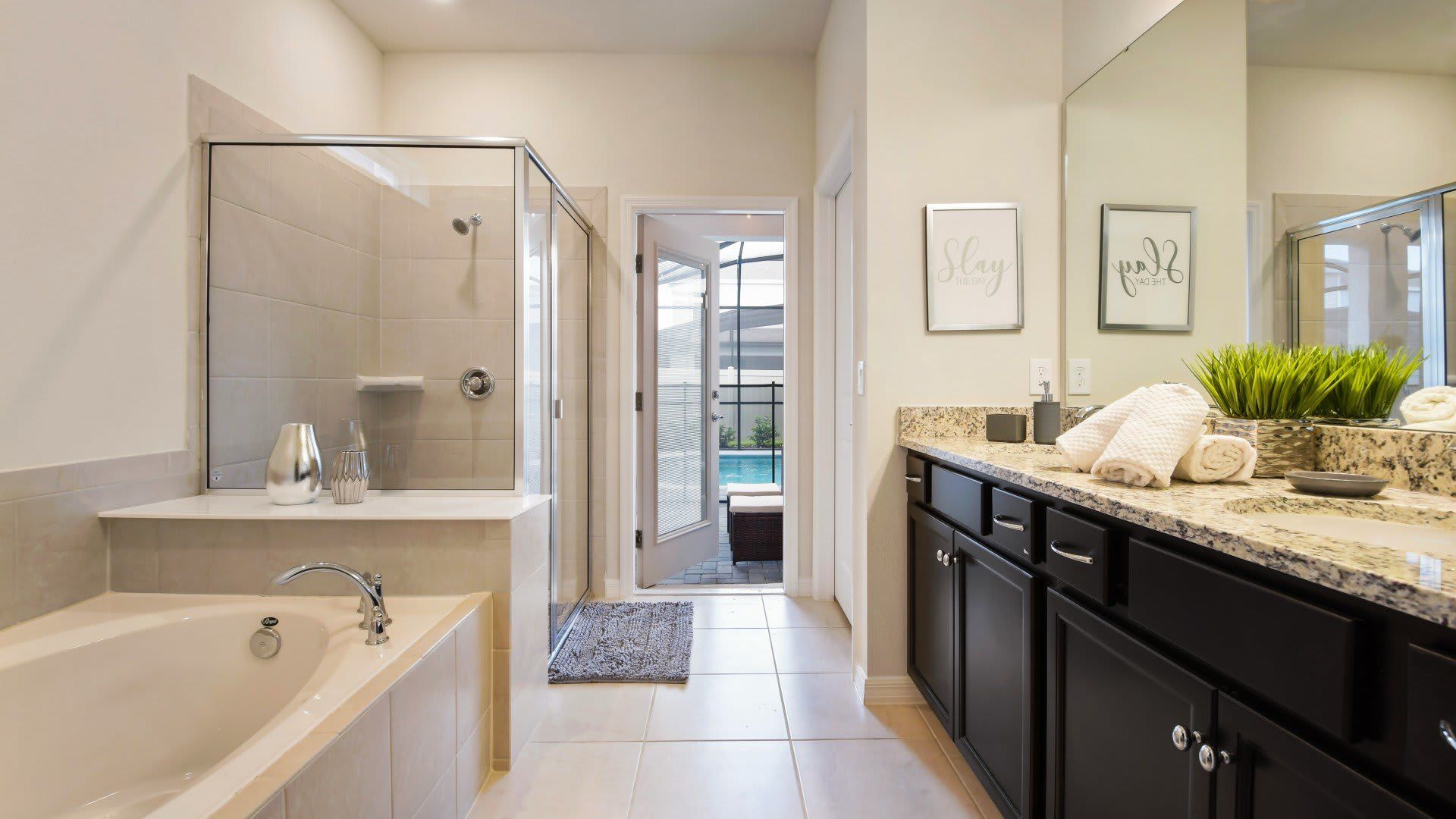 Luxury bathroom with soaking tub, dual vanity, walk-in shower, and poolside access.