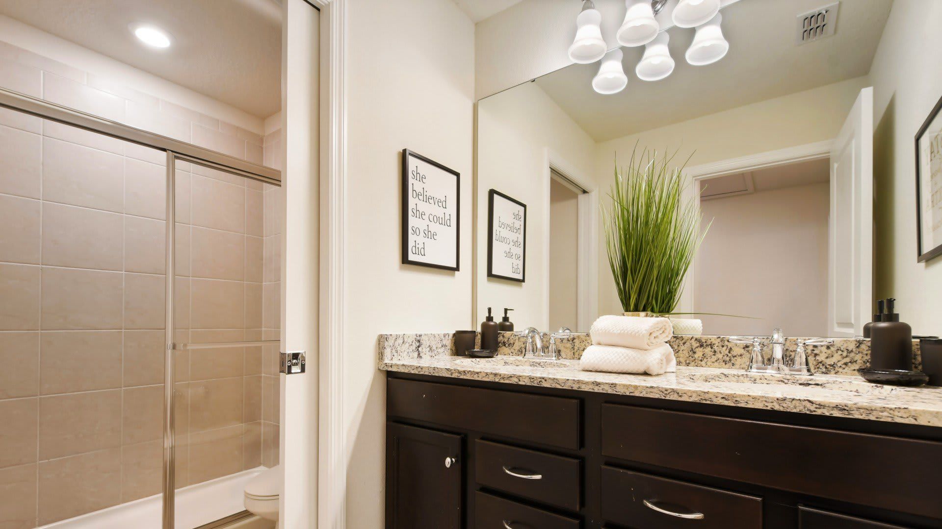 Modern bathroom with sleek finishes, granite countertop, and glass shower..