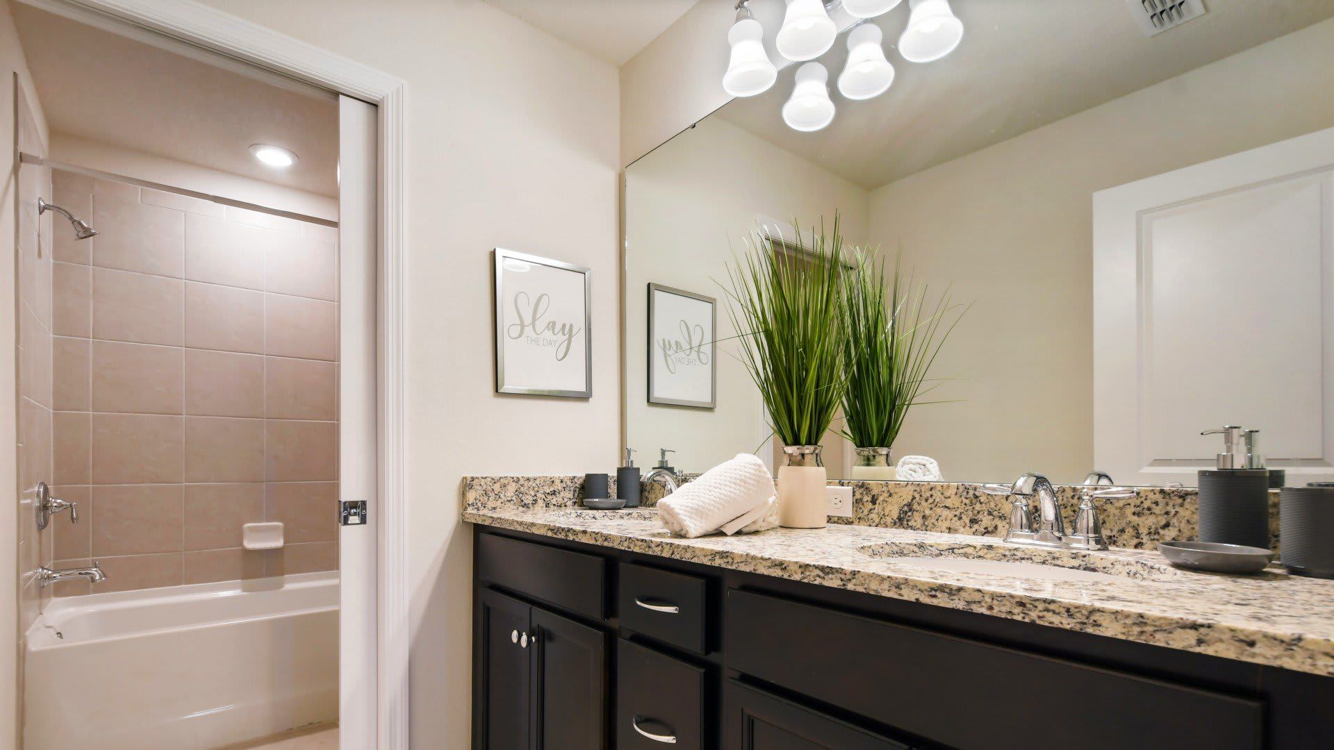 Stylish full bath with granite countertop, double vanity, and tiled shower-tub combo.