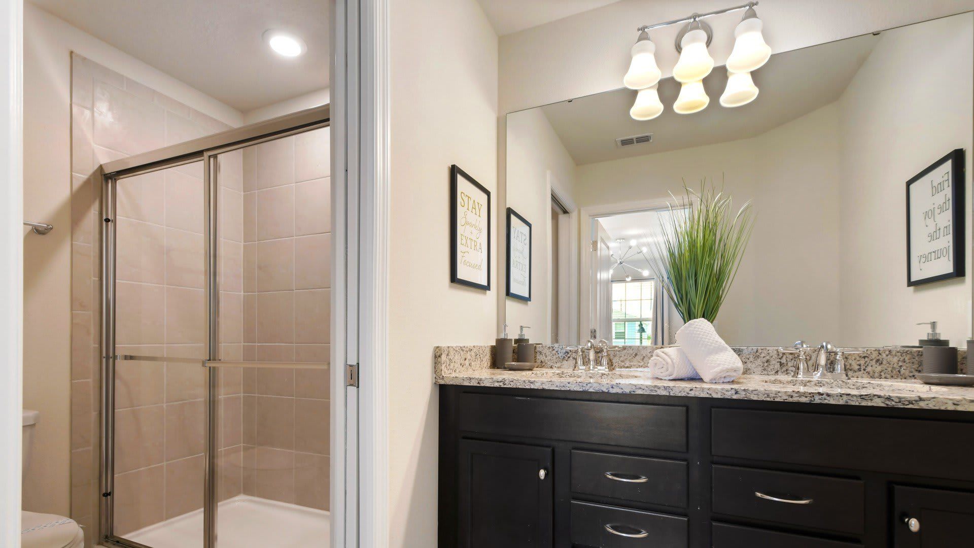 Contemporary bathroom with granite vanity, walk-in shower, and elegant lighting fixtures.