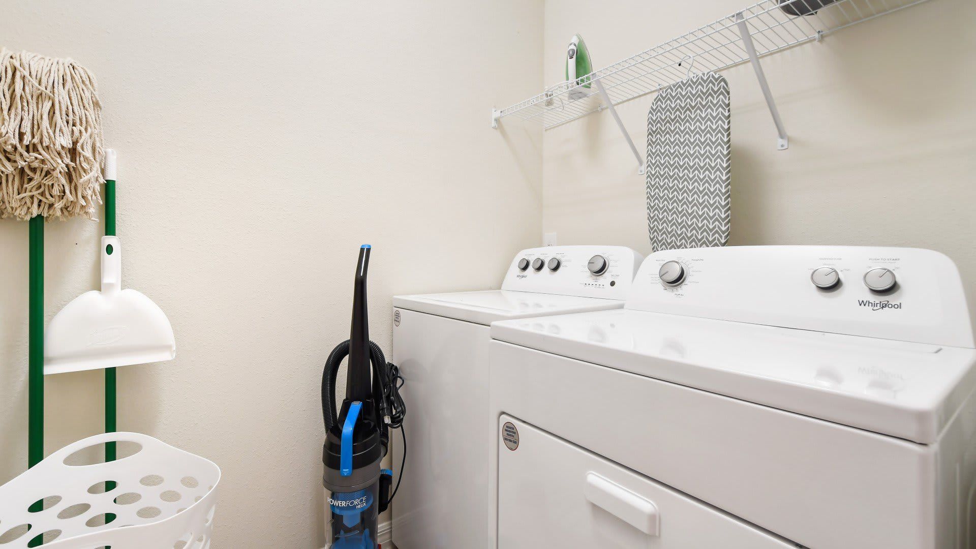 Fully equipped laundry room with washer, dryer, vacuum, and cleaning essentials.
