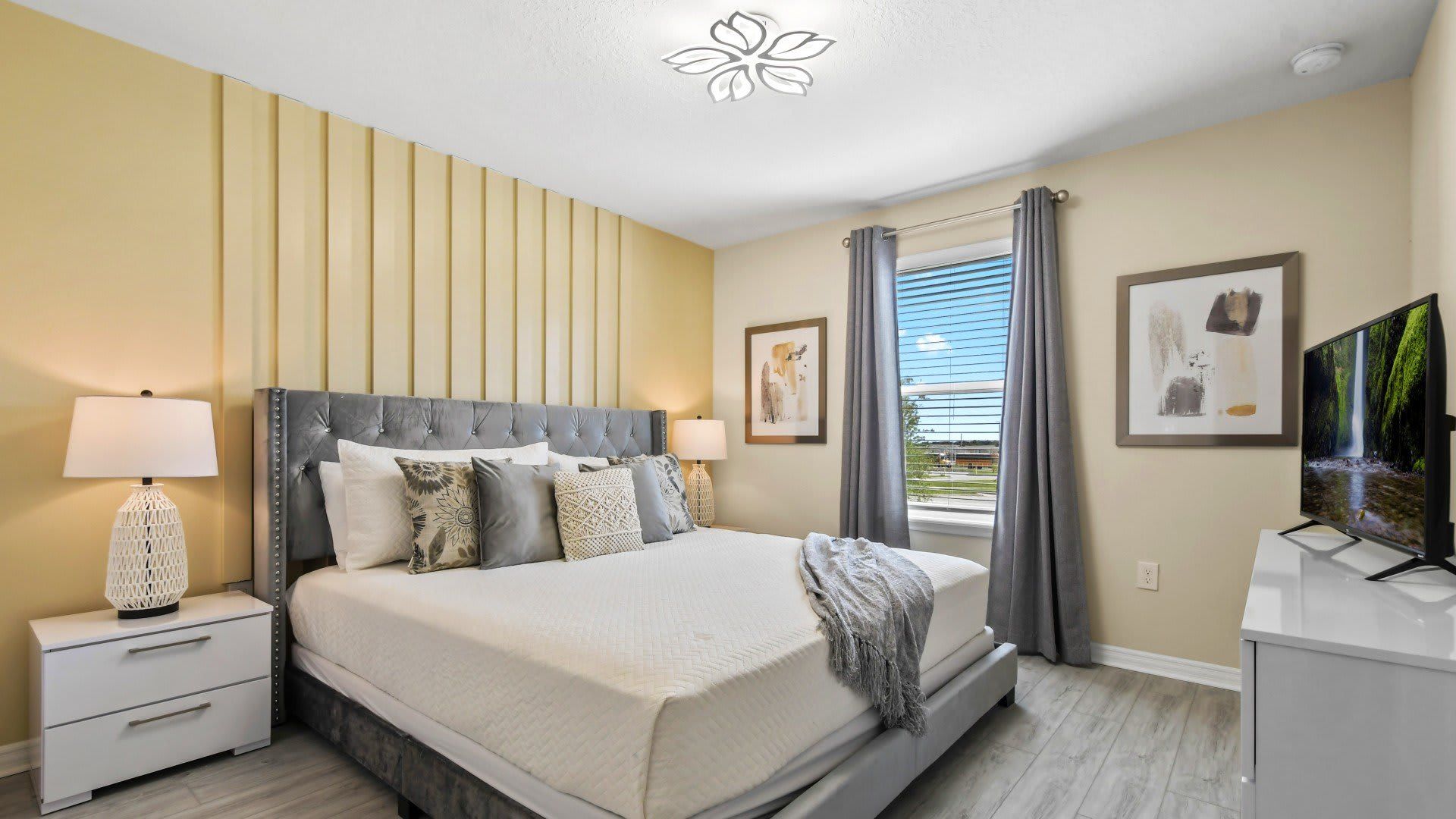 Bright and stylish bedroom with luxe tufted bed, TV, and peaceful natural tones.