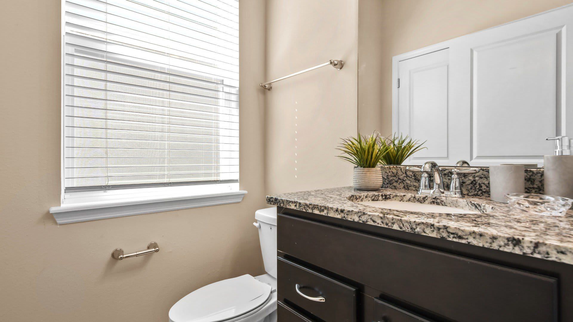 Bright and modern half bath with granite vanity and natural light charm.