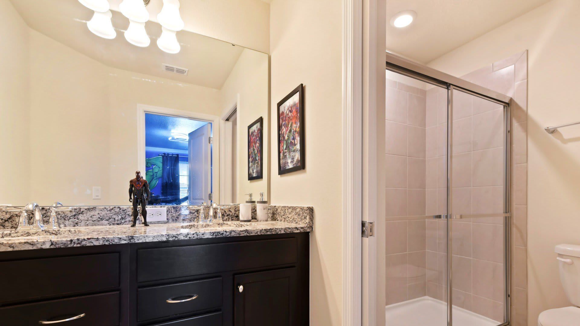 Modern bathroom with granite counters and walk-in shower near themed kids’ rooms.