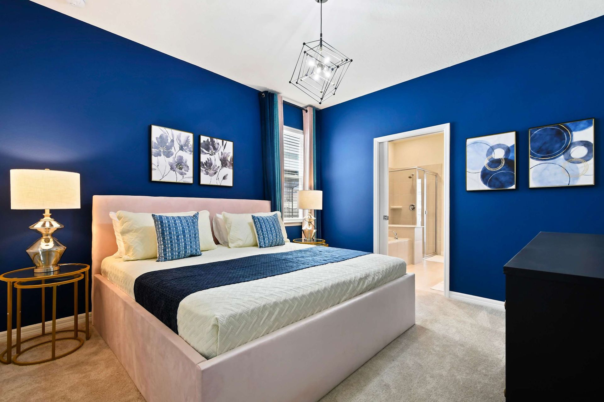 Modern king suite with bold navy walls, plush bedding, and private ensuite bath.